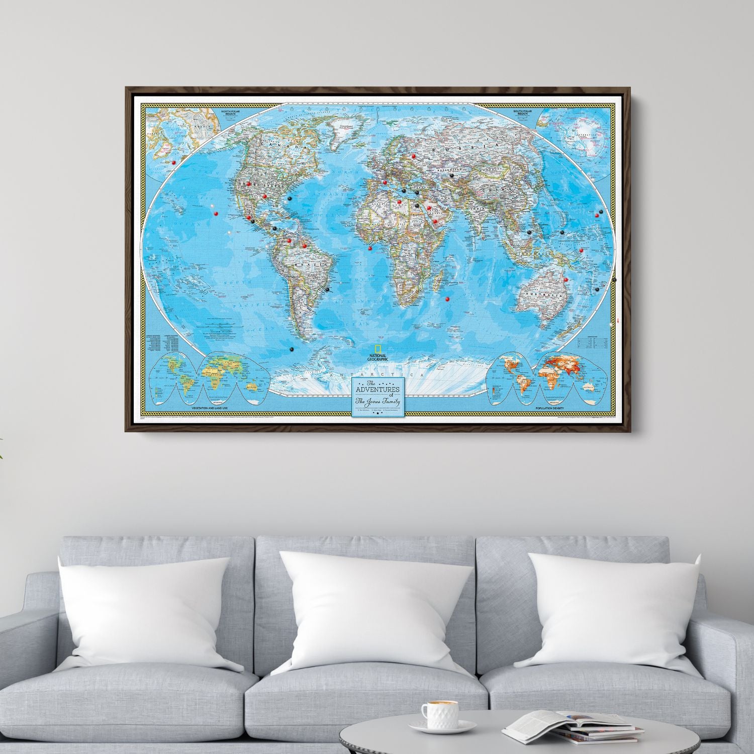 Framed National Geographic Classic World Travel Map canvas with red and black pins hanging above gray sofa