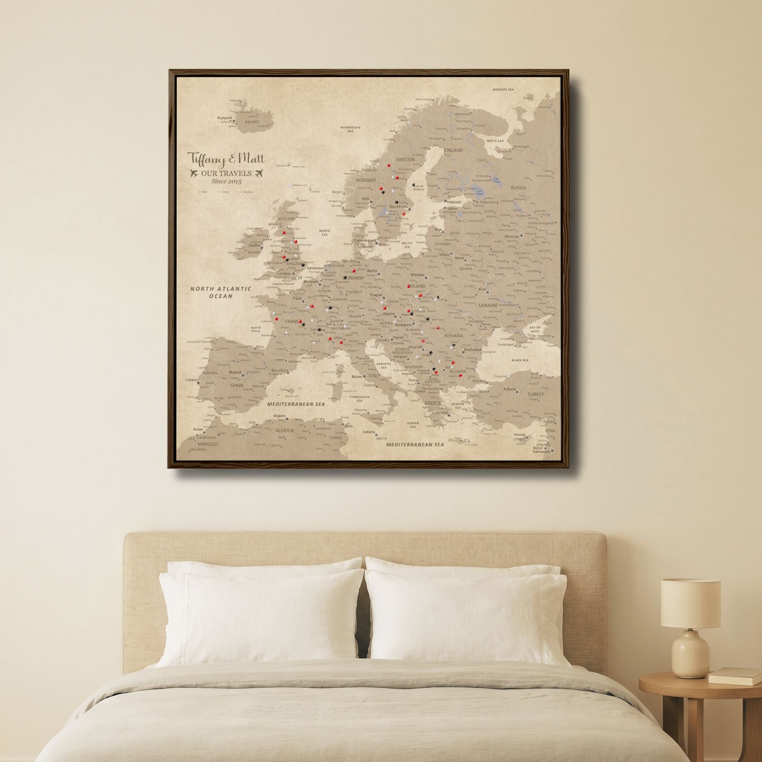 Personalized vintage Europe travel map canvas with red and black pins displayed above bedroom bed