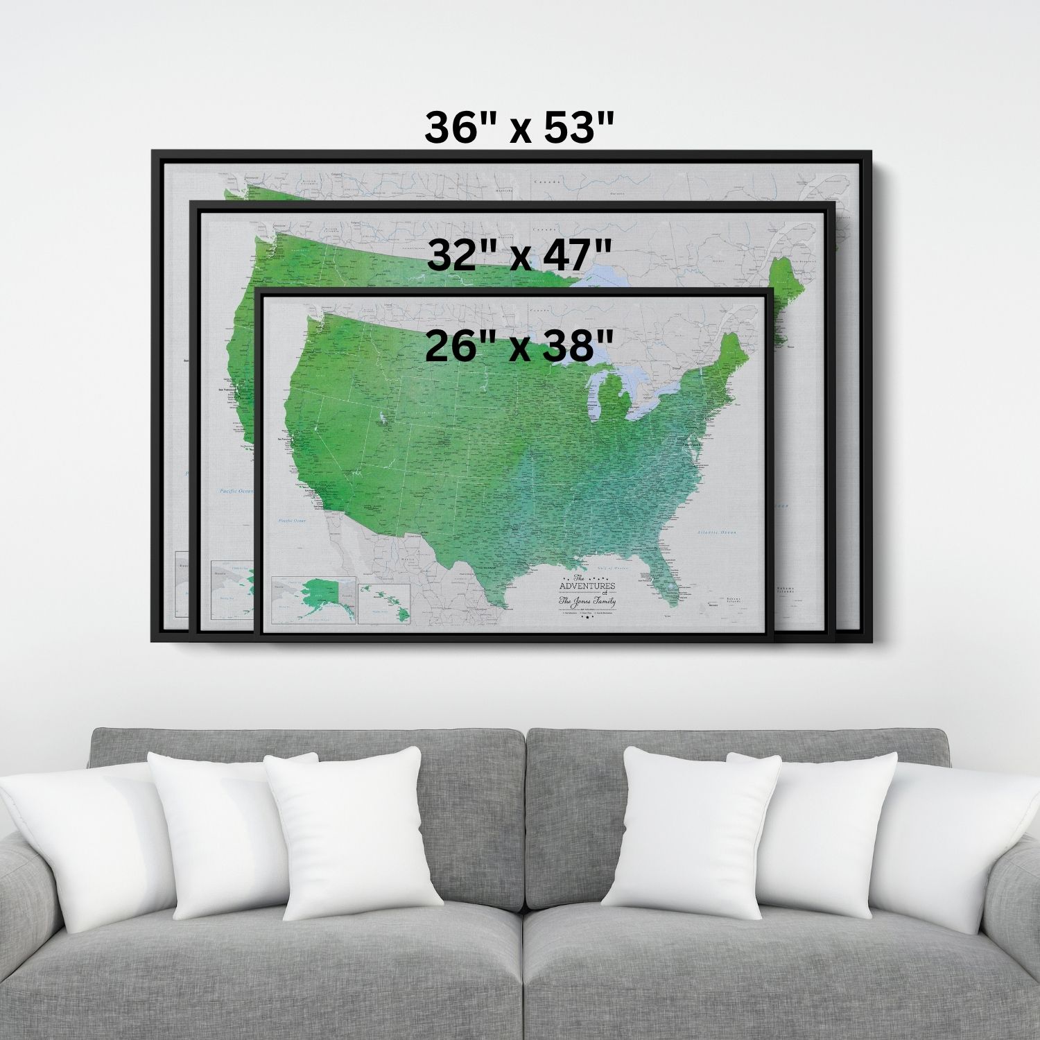 Three black-framed emerald watercolor USA travel map canvases displayed above gray sofa showing size comparison