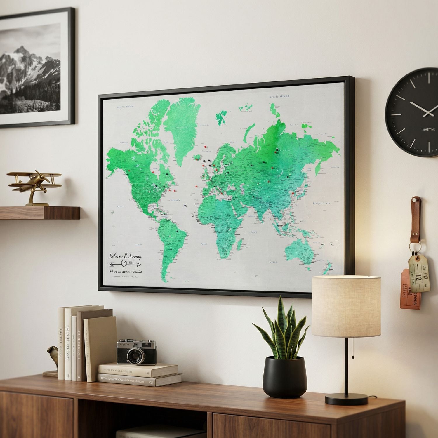 Personalized enchanting emerald watercolor world travel map with pins in black frame on living room wall