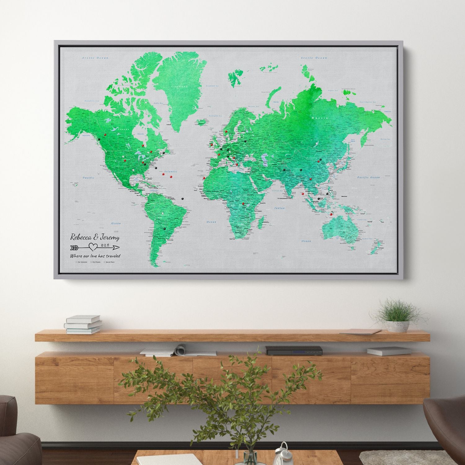 Enchanting Emerald watercolor world travel map canvas with push pins displayed above wooden shelf in modern living room