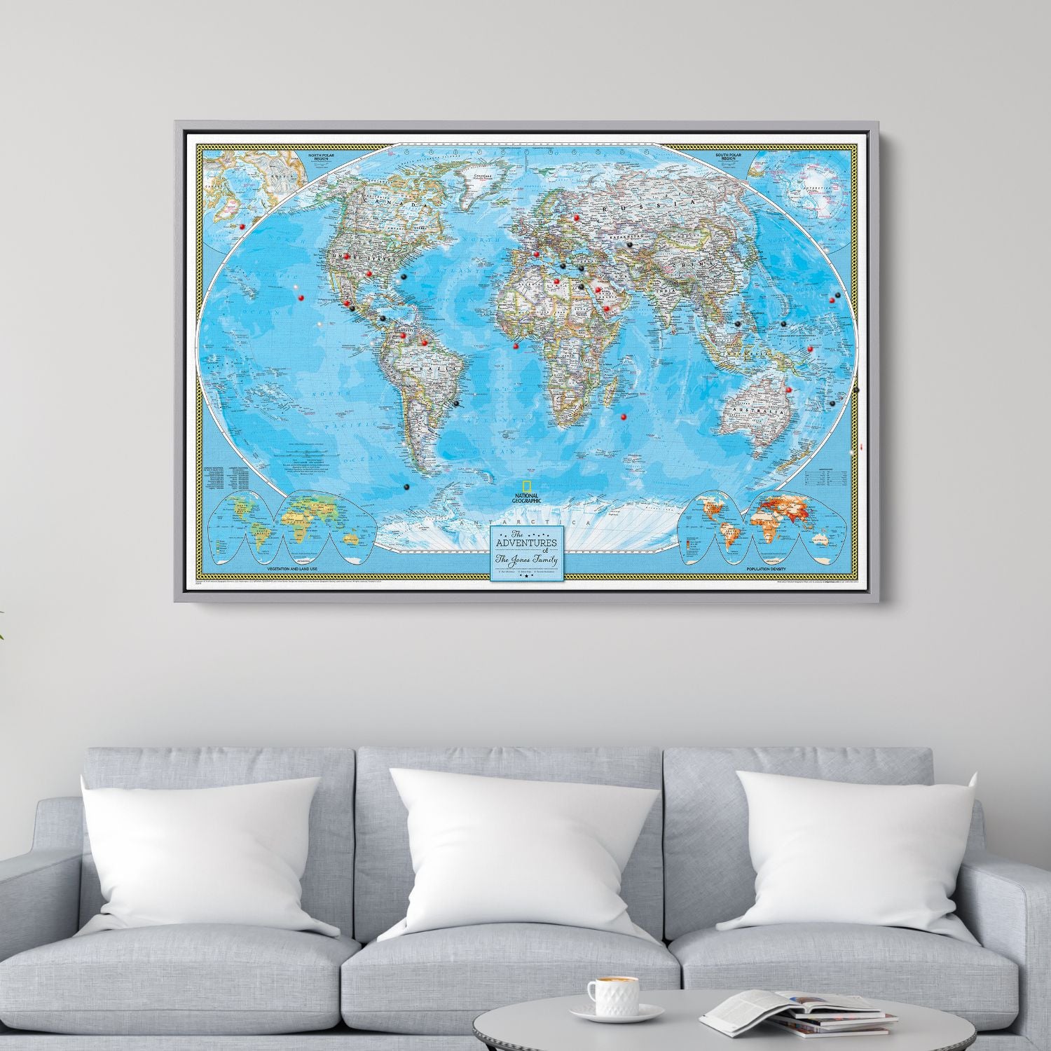 Framed National Geographic classic world travel map canvas with red and black pins hanging above gray sofa