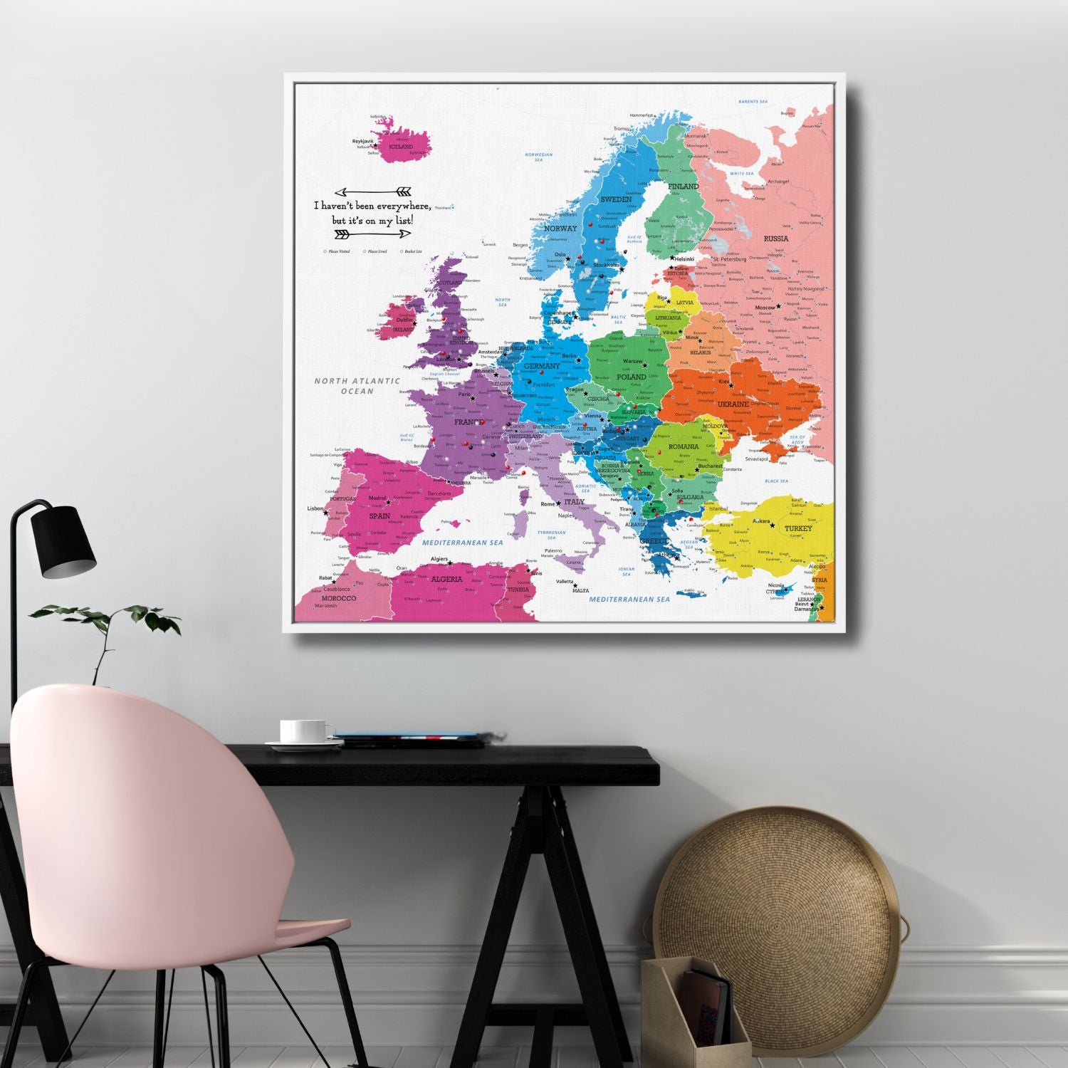 Colorful Europe travel map canvas with pins displayed above modern home office desk