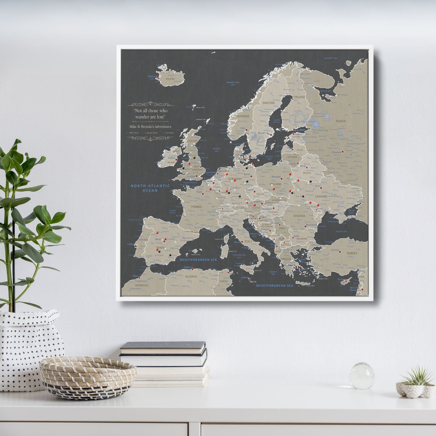 Earth toned Europe travel map canvas with red and black pins in white float frame displayed on wall
