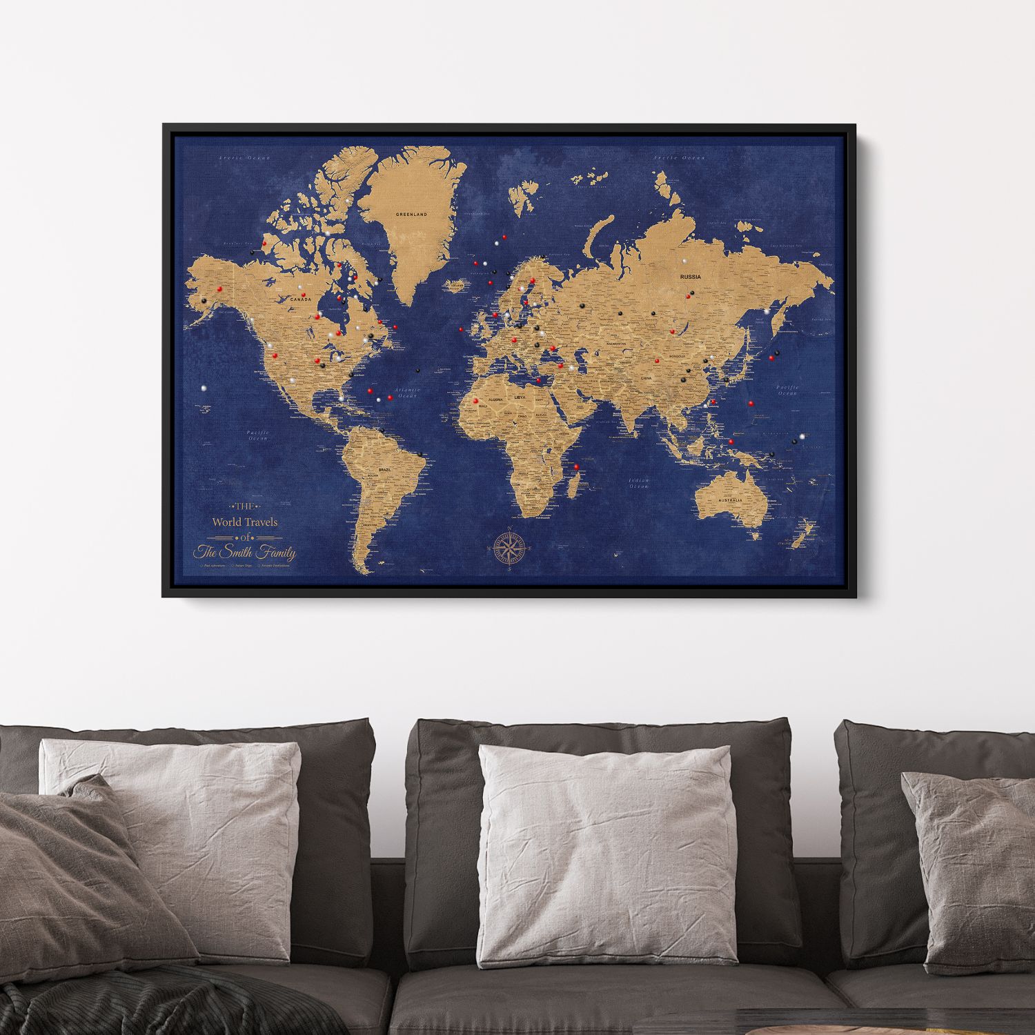Personalized gold and navy canvas world travel map with push pins displayed above gray sofa