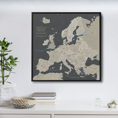 Earth toned Europe travel map canvas with red pins in black float frame hanging on white wall