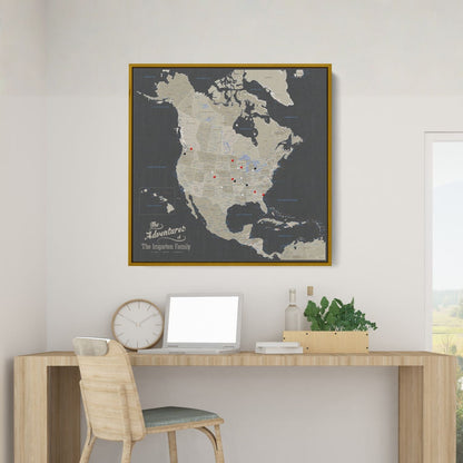 Personalized earth toned North America travel map with push pins in gold frame above modern desk