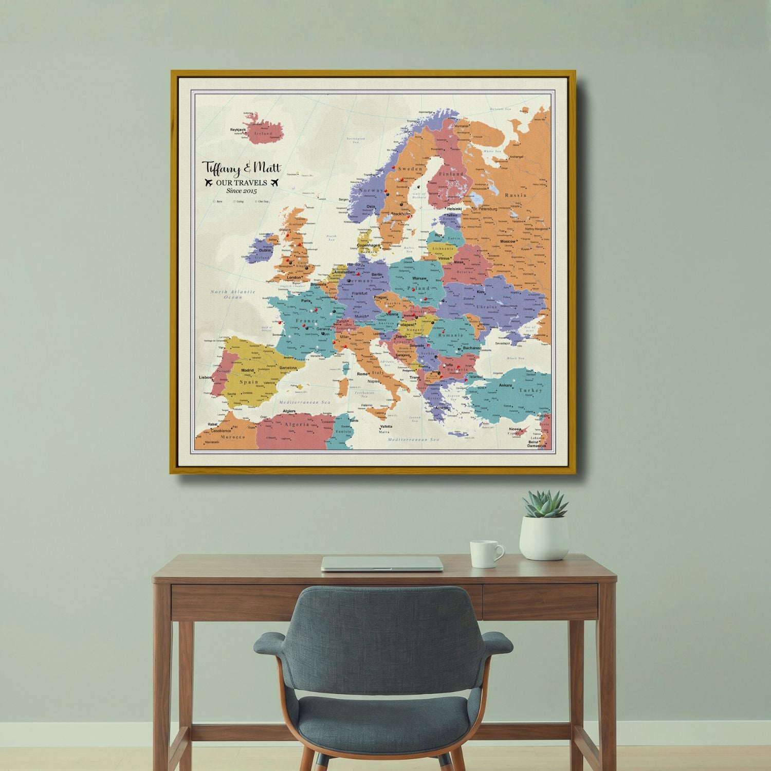 Personalized Europe push pin travel map canvas in gold frame hanging above wooden desk