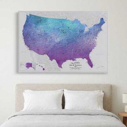 Vibrant violet watercolor USA push pin map canvas hung above bedroom bed with colorful travel pins