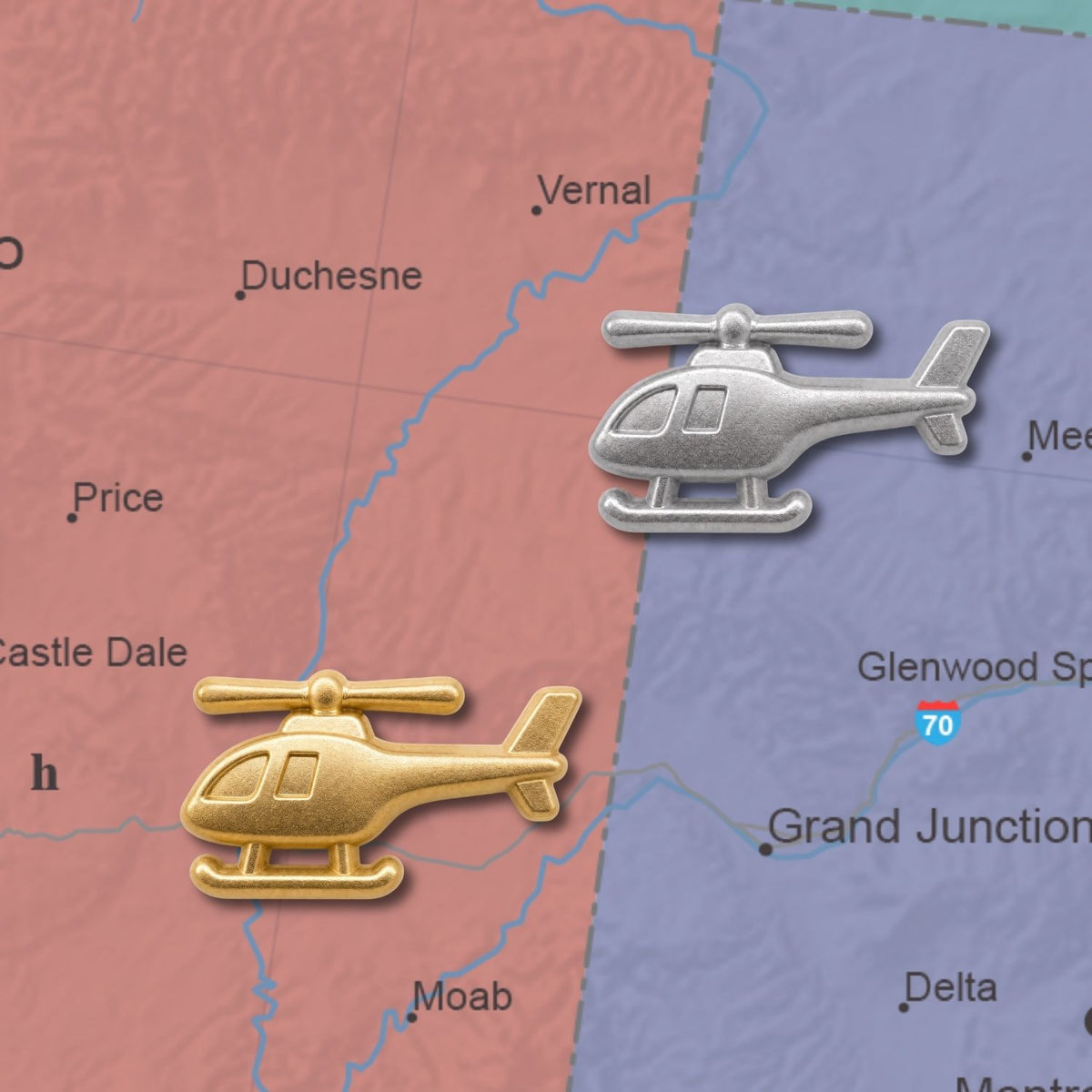 Gold and silver 3D metal helicopter push pins placed on a colorful road map
