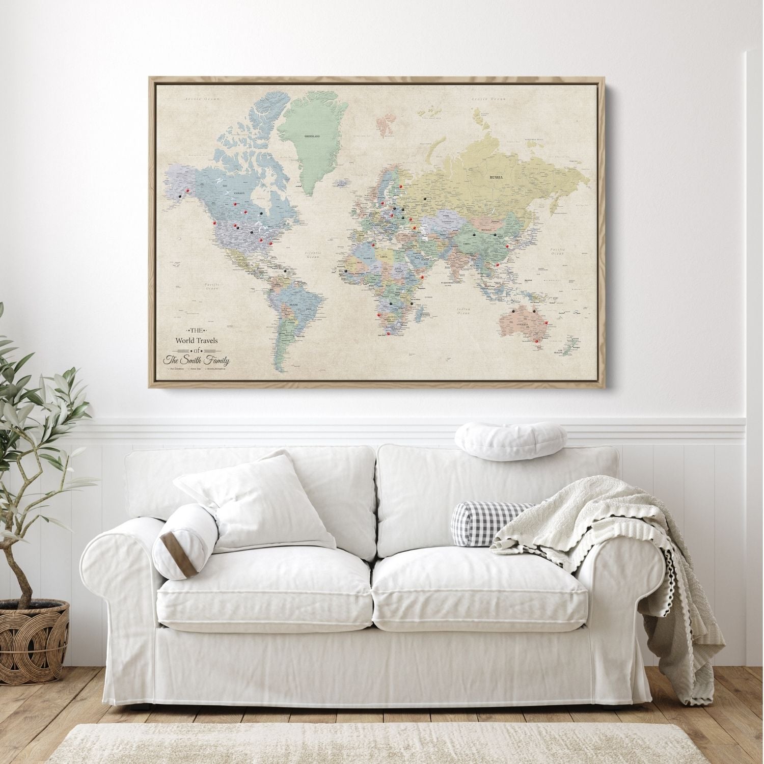 Personalized Sandy Dreams world travel map canvas in natural float frame with red and black push pins hung above white sofa