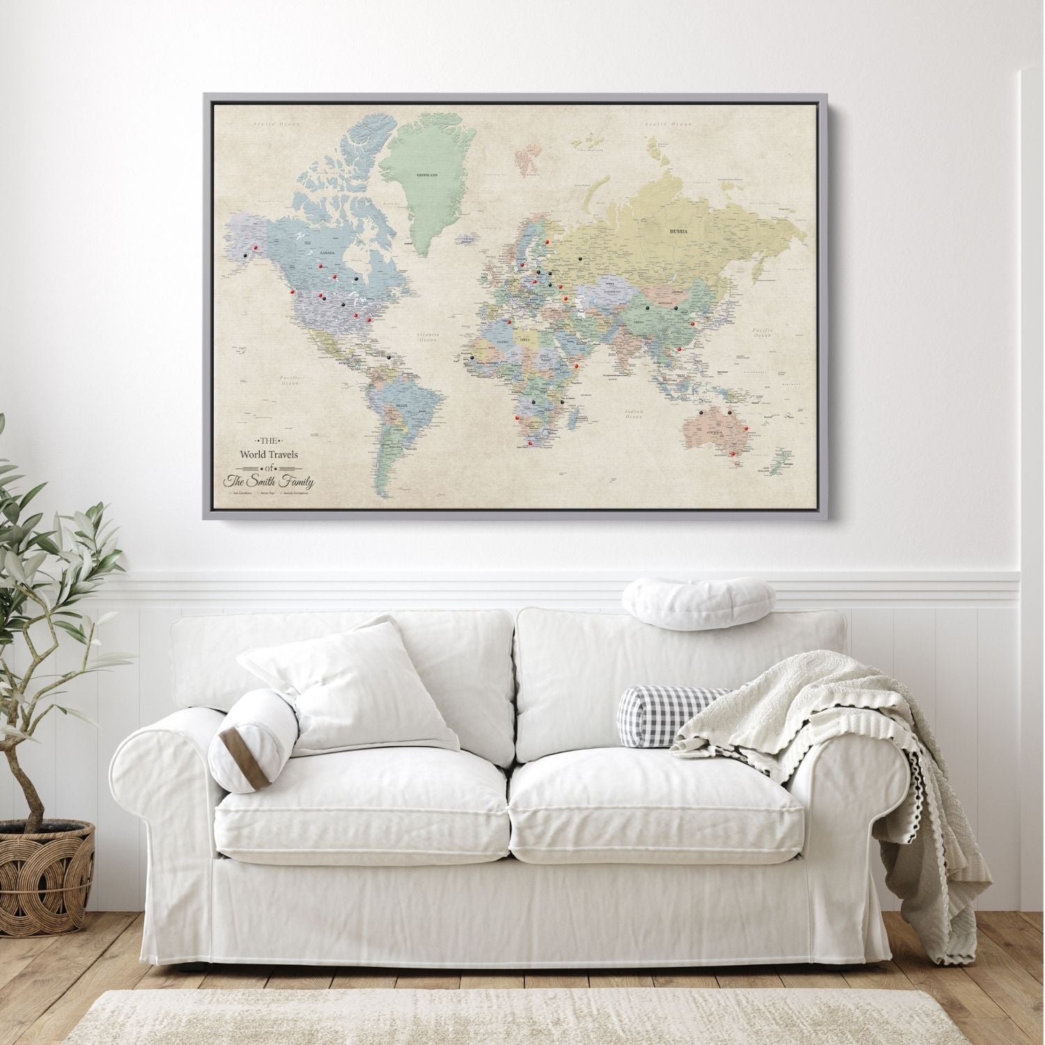 Personalized Sandy Dreams world travel map canvas in silver float frame with red and black push pins hung above white sofa