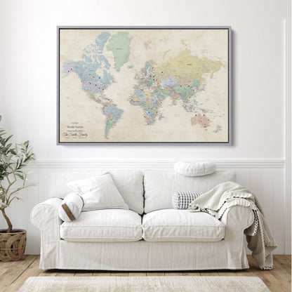 Personalized Sandy Dreams world travel map canvas in silver float frame with red and black push pins hung above white sofa